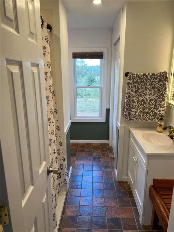 full bath with vanity, curtained shower, baseboards, and stone tile floors