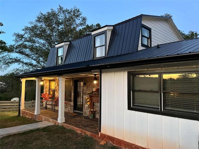 back of property featuring board and batten siding, a patio area, a gambrel roof, and metal roof