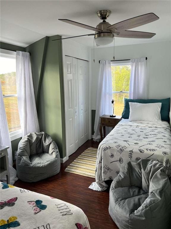 bedroom with a closet, baseboards, wood finished floors, and a ceiling fan