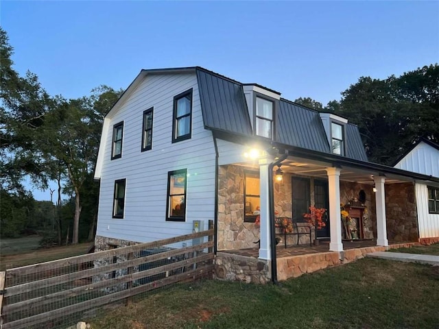 exterior space featuring a yard, fence, a gambrel roof, and metal roof