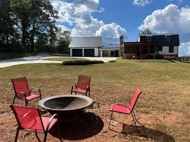 exterior space featuring concrete driveway, a garage, a sunroom, and an outdoor fire pit