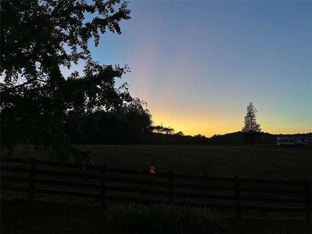 yard at dusk with a rural view and fence