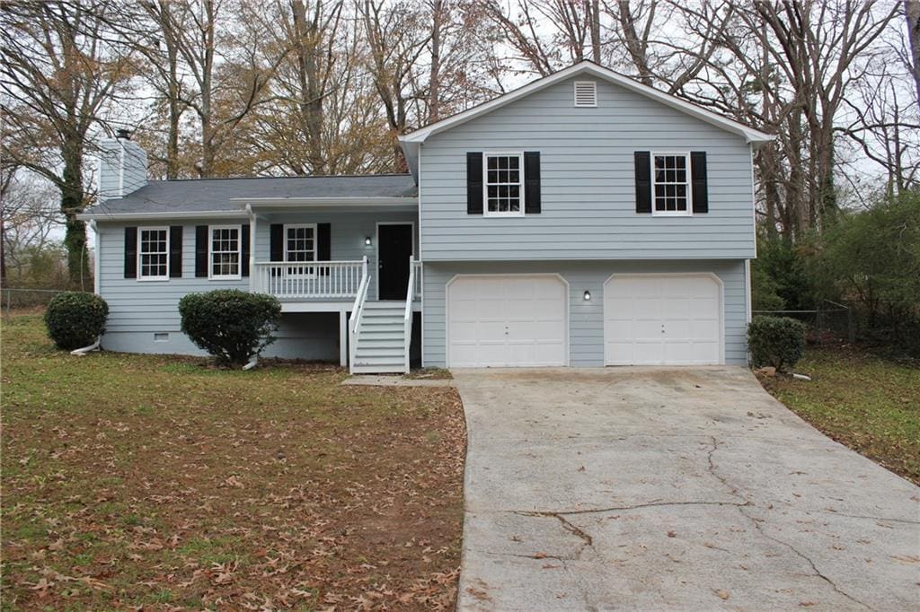 split level home featuring a porch, a garage, and a front lawn