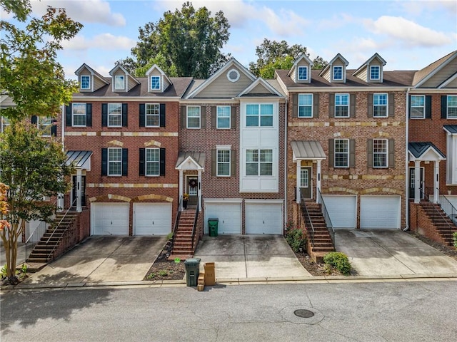 townhome / multi-family property featuring stairs, driveway, and brick siding