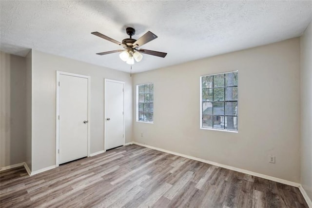 703 Pine Tree Trl, Atlanta, GA 30349 - unfurnished bedroom with ceiling fan, light hardwood / wood-style floors, a textured ceiling, and multiple closets