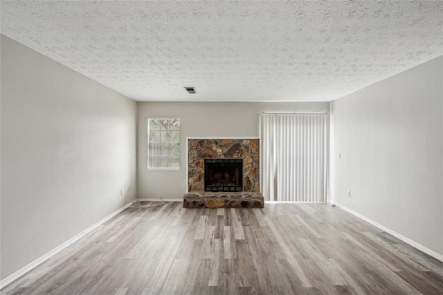 703 Pine Tree Trl, Atlanta, GA 30349 - unfurnished living room with a textured ceiling, a fireplace, and wood-type flooring