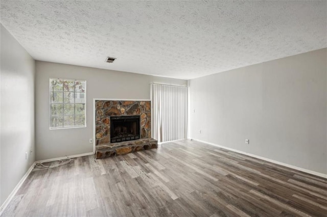 703 Pine Tree Trl, Atlanta, GA 30349 - unfurnished living room with a textured ceiling, wood-type flooring, and a stone fireplace