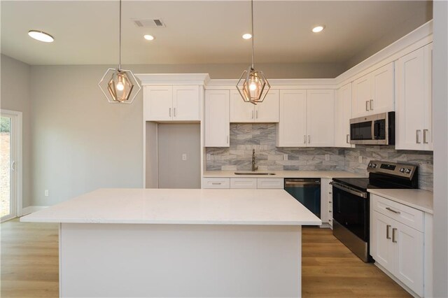 kitchen with a kitchen island, white cabinetry, appliances with stainless steel finishes, and sink