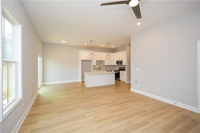 unfurnished living room with plenty of natural light, ceiling fan, and light wood-type flooring