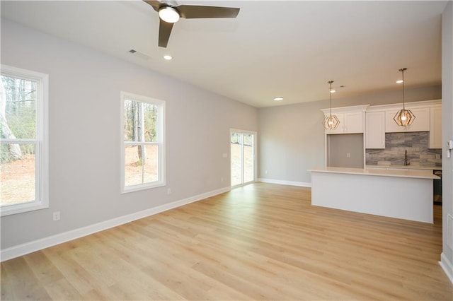 unfurnished living room with ceiling fan and light wood-type flooring