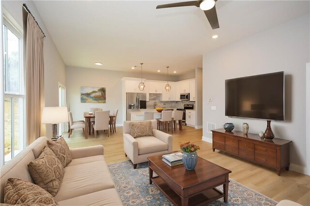 living room with ceiling fan, plenty of natural light, and light hardwood / wood-style floors