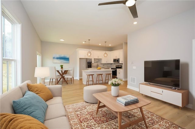 living room featuring light hardwood / wood-style floors and ceiling fan