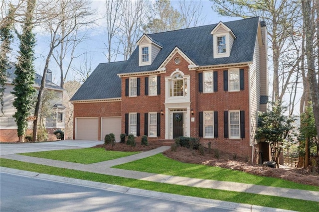 view of front facade featuring brick siding, concrete driveway, a front yard, and a shingled roof