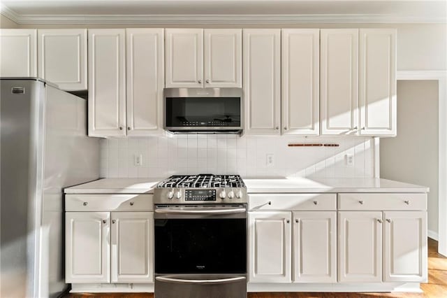 kitchen featuring decorative backsplash, appliances with stainless steel finishes, white cabinets, and light countertops