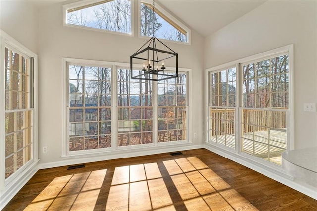 unfurnished sunroom featuring visible vents, a healthy amount of sunlight, a chandelier, and vaulted ceiling