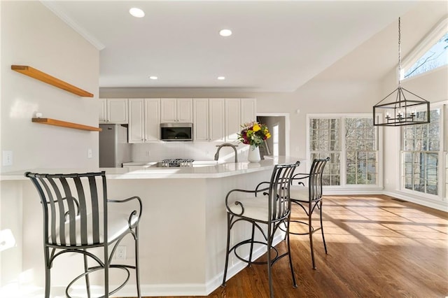 kitchen featuring wood finished floors, open shelves, white cabinets, appliances with stainless steel finishes, and a chandelier