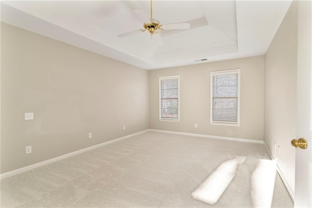 carpeted spare room with baseboards, a raised ceiling, visible vents, and ceiling fan