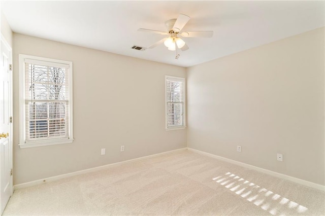 carpeted empty room with a ceiling fan, baseboards, and visible vents