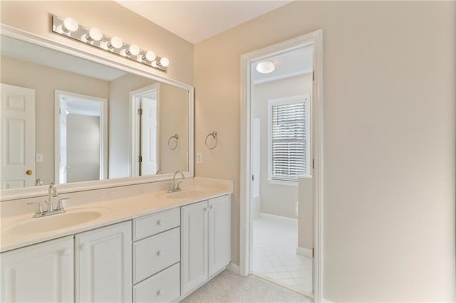 bathroom featuring a sink, baseboards, double vanity, and tile patterned floors