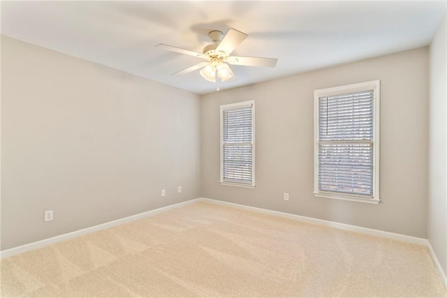 empty room featuring light colored carpet, baseboards, and a ceiling fan