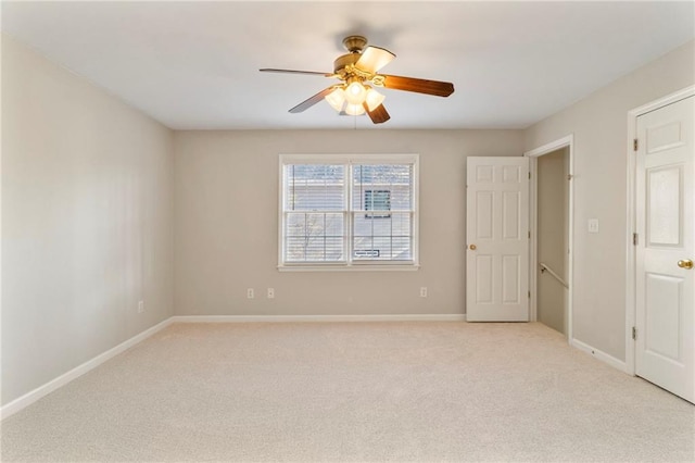 unfurnished room with light colored carpet, baseboards, and a ceiling fan