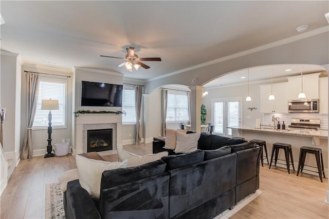 6410 Crosscreek Ln, Flowery Branch, GA 30542 - living room featuring arched walkways, a ceiling fan, light wood finished floors, a fireplace, and decorative columns
