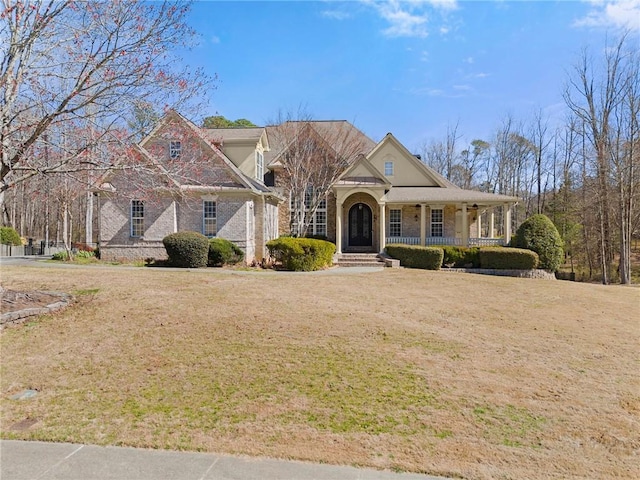 view of front of home with covered porch, brick siding, and a front lawn