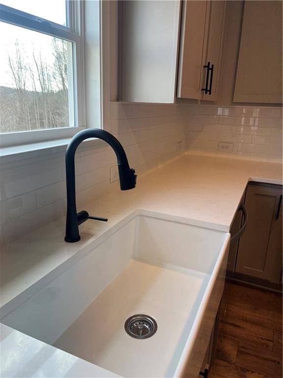 details with a sink, decorative backsplash, dark wood-type flooring, and light countertops