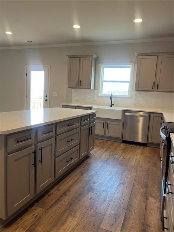 kitchen featuring gray cabinetry, ornamental molding, a sink, dark wood-style floors, and appliances with stainless steel finishes