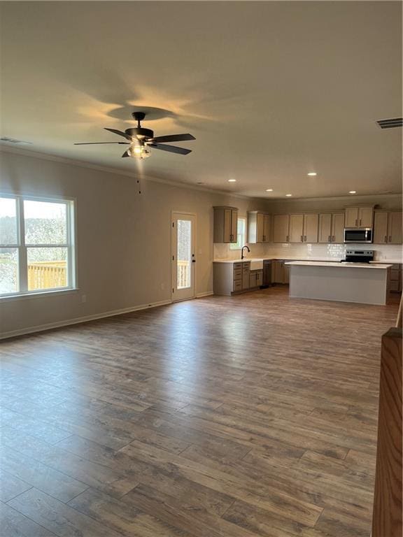 unfurnished living room featuring visible vents, dark wood-style floors, crown molding, baseboards, and ceiling fan