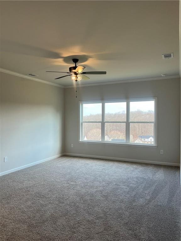 carpeted spare room featuring a wealth of natural light, visible vents, ceiling fan, and ornamental molding