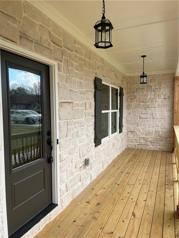 view of exterior entry featuring stone siding and a porch