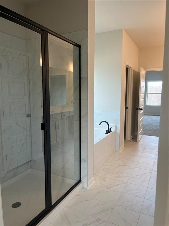 bathroom with marble finish floor, a shower stall, and a garden tub