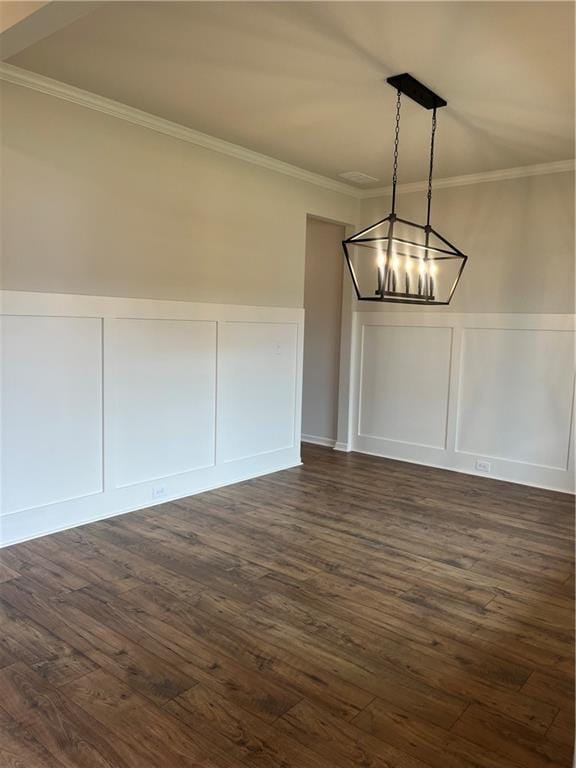 unfurnished dining area with dark wood finished floors, an inviting chandelier, and crown molding