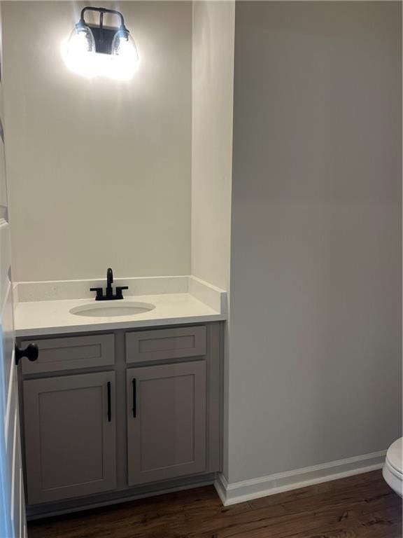 bathroom featuring toilet, vanity, baseboards, and wood finished floors