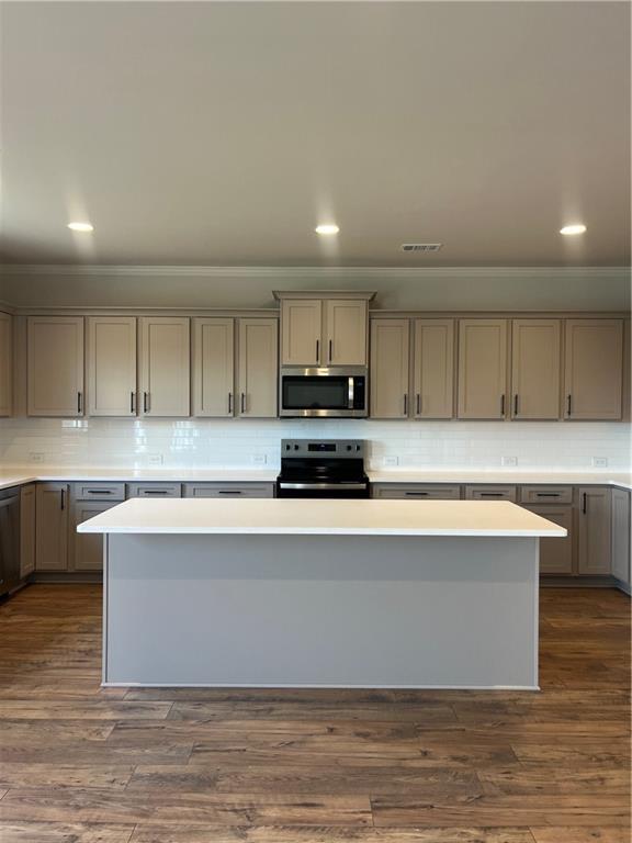 kitchen with gray cabinetry, stainless steel appliances, light countertops, and dark wood-style flooring