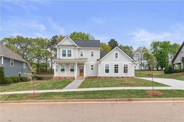 traditional home featuring metal roof, board and batten siding, a front lawn, and covered porch