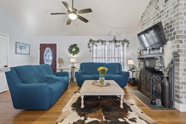 living room featuring lofted ceiling, hardwood / wood-style flooring, a fireplace, and ceiling fan