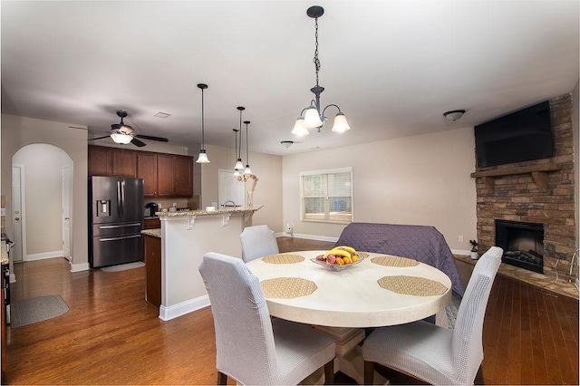 3631 Guinevere Trce, Douglasville, GA 30135 - dining area with a stone fireplace, arched walkways, dark wood-style flooring, and a ceiling fan