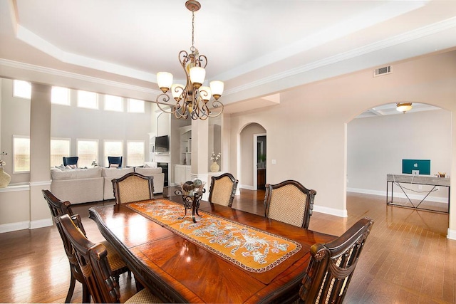 3631 Guinevere Trce, Douglasville, GA 30135 - dining area with arched walkways, a chandelier, wood finished floors, a tray ceiling, and crown molding