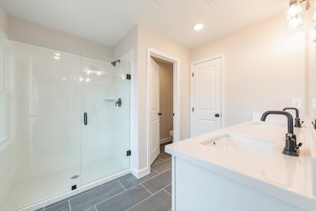 bathroom with a shower with door, vanity, and toilet