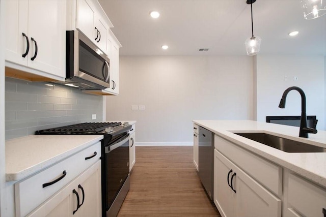 kitchen with stainless steel appliances, white cabinetry, sink, and decorative backsplash