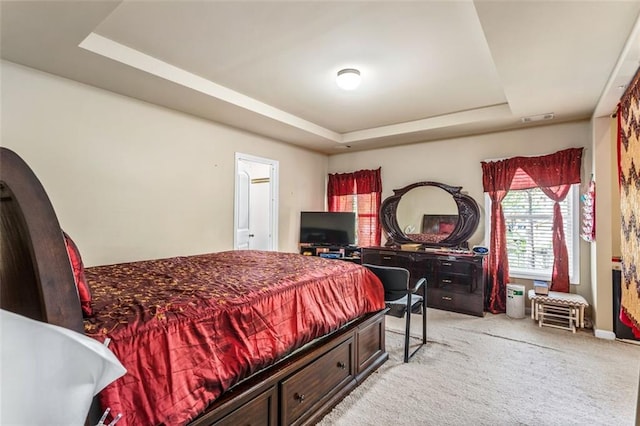 bedroom with visible vents, baseboards, a tray ceiling, and light carpet