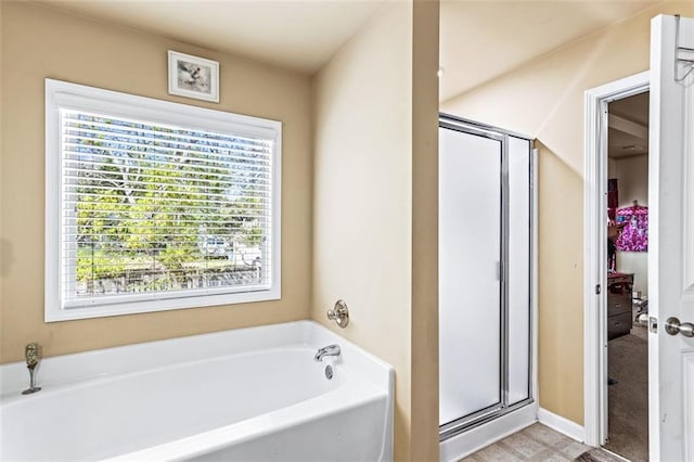 bathroom featuring plenty of natural light, a bath, and a shower stall