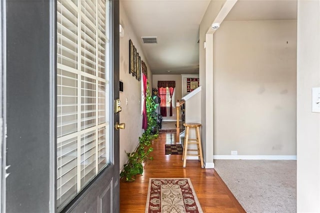 hall with stairway, baseboards, wood finished floors, and visible vents