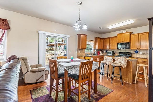 dining space with a toaster, light wood finished floors, and a notable chandelier