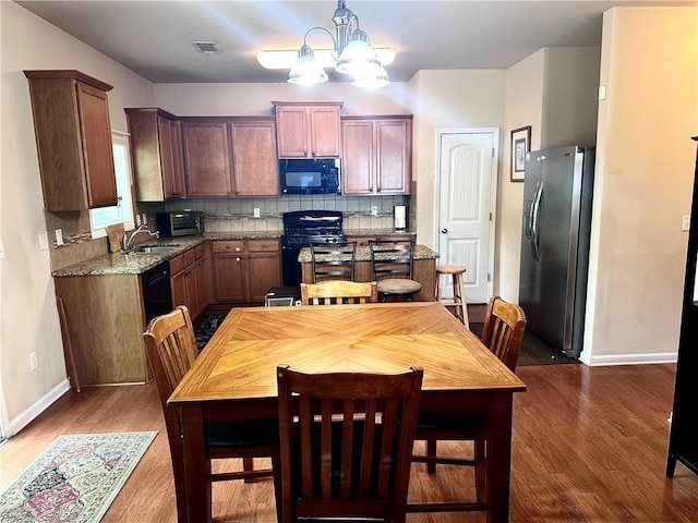 kitchen featuring a notable chandelier, baseboards, wood finished floors, visible vents, and black appliances