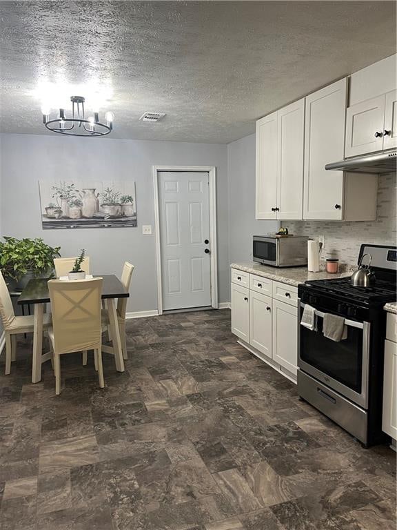 kitchen featuring a textured ceiling, white cabinetry, an inviting chandelier, stainless steel appliances, and decorative backsplash