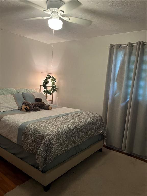 carpeted bedroom featuring ceiling fan and a textured ceiling