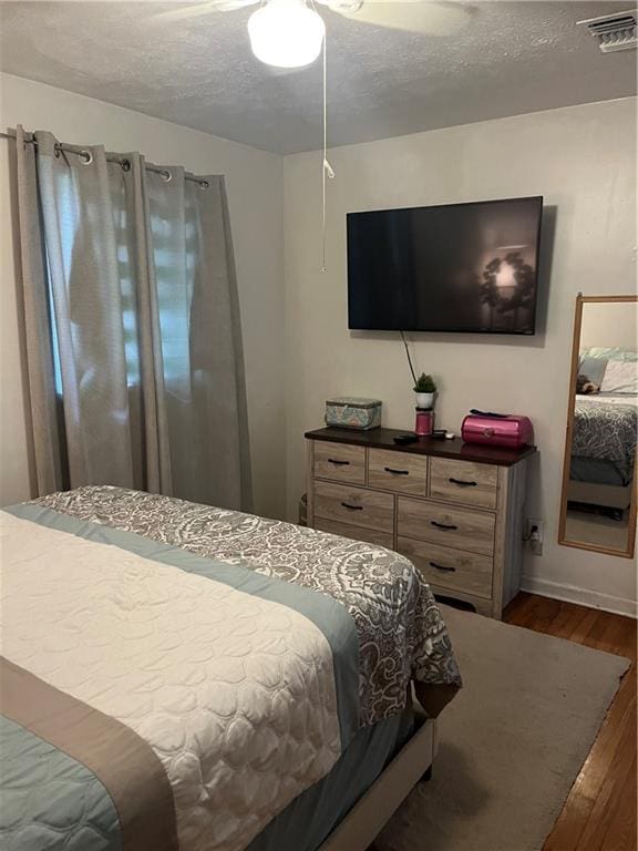 bedroom featuring ceiling fan, a textured ceiling, and dark wood-type flooring